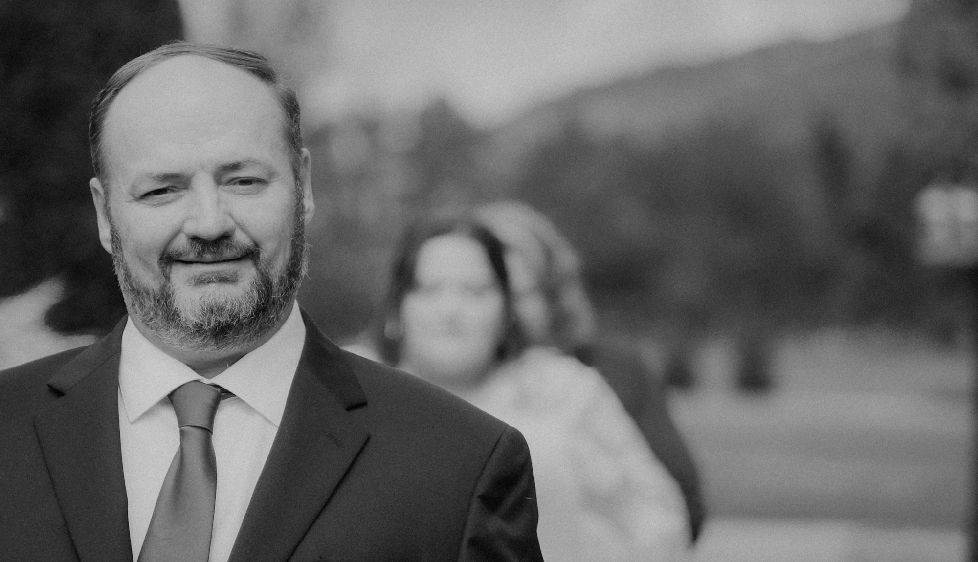 Un homme âgé en costume, boutonnière à la boutonnière, pendant un discours de mariage